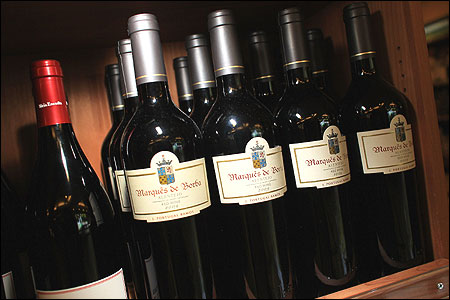 Bottles of red wine line a shelf.