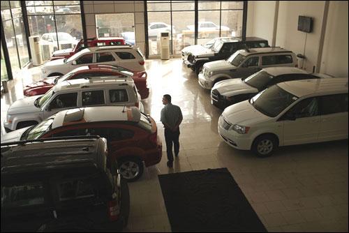 A man walks through a car showroom.