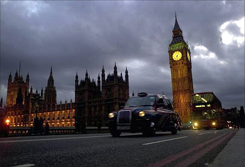 A bus and taxi pass Big Ben on Westminster Bridge in London.