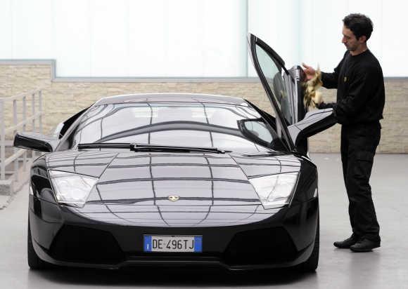 A technician cleans a door of a Lamborghini Murcielago.