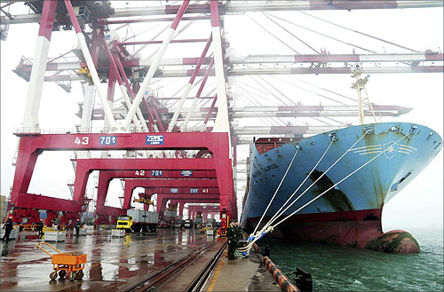 Employees unload containers from a cargo ship as frontier inspection soldiers (C) stand guard at Qingdao port during a rainy day in Qingdao, Shandong province.
