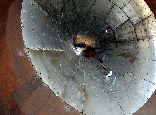 A labourer welds a giant funnel which will be used in a coal-burning power plant in Huaibei, Anhui province.