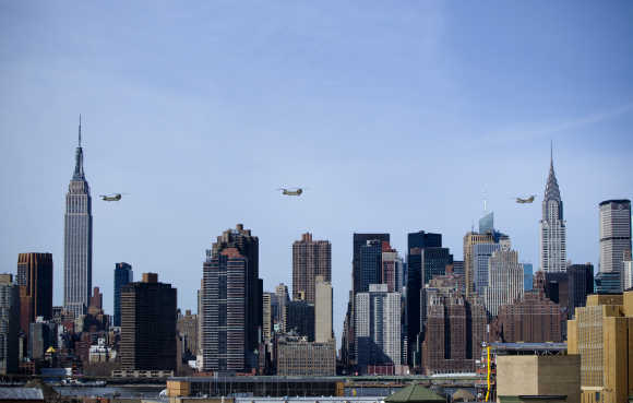 Three US Army CH-47 Chinook helicopters with 10th Combat Aviation Brigade's 6-6 Cavalry fly past skyline of New York.