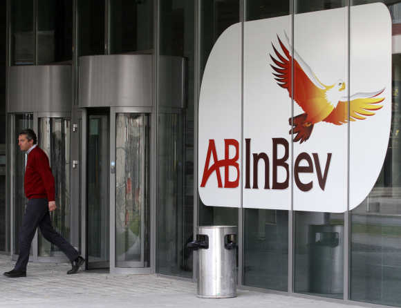A man walks past a logo at the headquarters of Anheuser-Busch InBev in St Louis, Missouri, US.