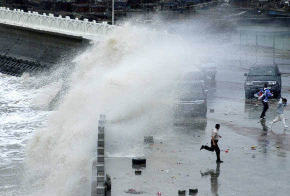 People run away from big waves affected by Typhoon Krosa at a levee in Lianyungang, China.