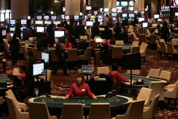 Dealers wait for customers at the casino inside Melco Crown Entertainment's latest gaming resort City of Dreams in Macau.