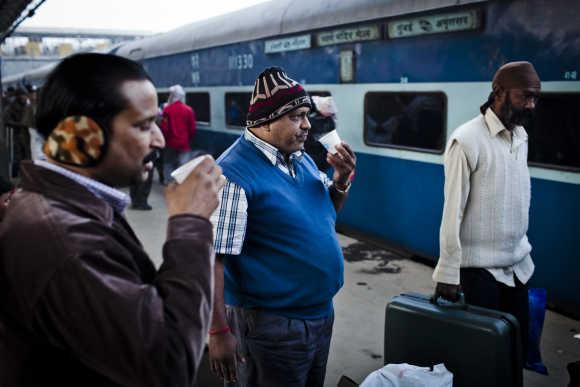 Men drink tea on the platform prior to departing from the Nizamuddin Railway Station in New Delhi.