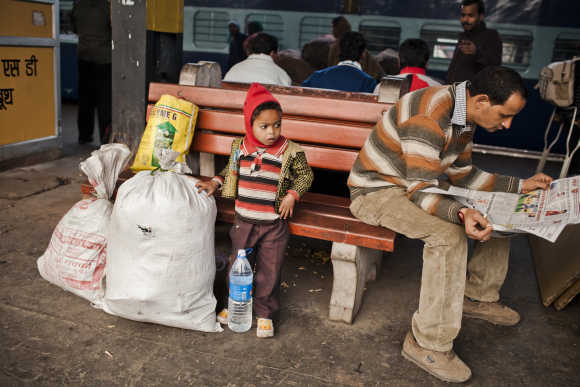 A boy waits with his family belongings prior to boarding a train at the Nizamuddin Railway Station.