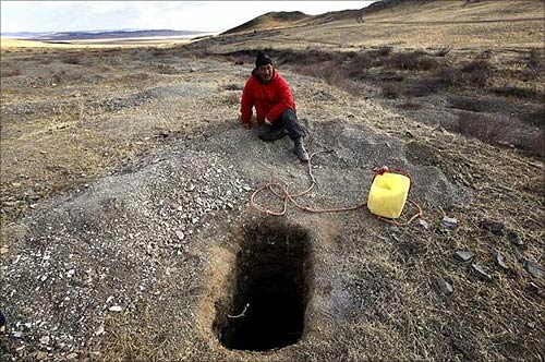 A small-scale miner rests next to a 15-feet (4.6-metre) deep hole he dug searching for gold on a small hill overlooking grasslands located around 200 km (125 miles) south-west of the Mongolian capital city Ulan Bator.