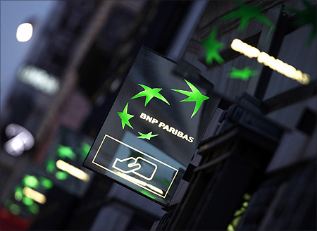 Illuminated signs light up at twilight outside the headquarters of the BNP Paribas bank in Paris.