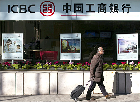A man carries a case as he walks past the new branch of China's Industrial and Commercial Bank of China (ICBC) in central Madrid.