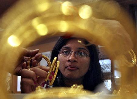 A customer looks at gold bangles inside a jewellery showroom.