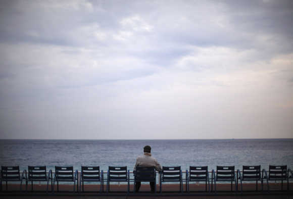 A man sits and looks out to sea on Promenade des Anglais in Nice, France.