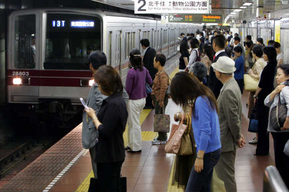 Passengers wait for a train on a platform at Tokyo Metro's Hibiya station.