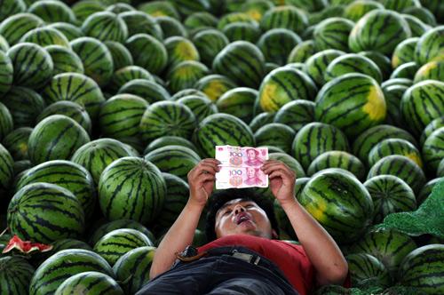 A watermelon vendor looks at yuan banknotes at a market in Changzhi, Shanxi province.