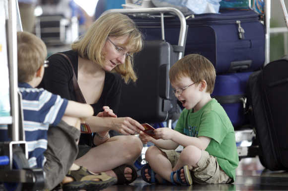 Lawrence Jones, four, plays cards with his mother Susan Hourihan and brother Harvey as they wait for their flight to London, at Kuala Lumpur International Airport.