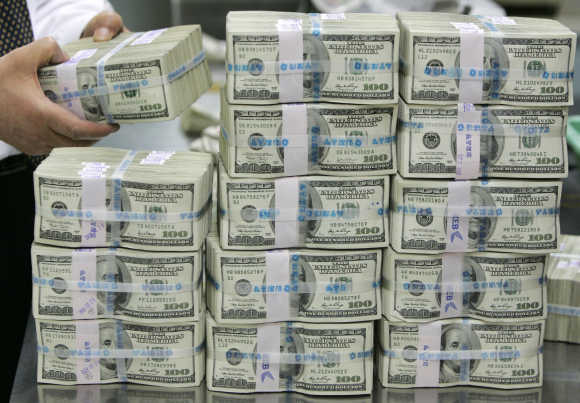A bank employee counts one hundred dollar notes at a bank.