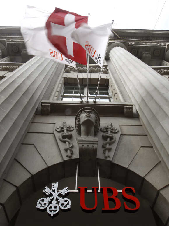 A Switzerland national flag flies over the logo of Swiss bank UBS at a branch office in Zurich.