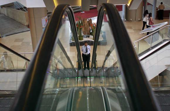 A private security personnel stands guard between escalators inside a shopping mall in Mumbai.