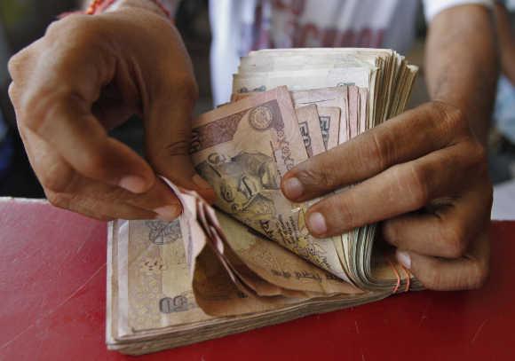 A grocery shop owner counts rupees in Ahmedabad.