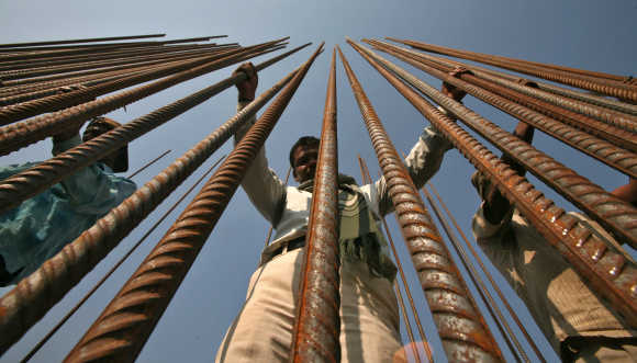 Workers hold iron rods at a construction site of a bridge on the river Tawi in Jammu.