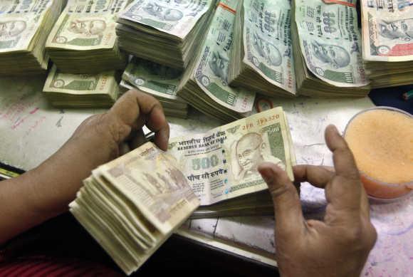 An employee counts currency notes at a cash counter inside a bank in Kolkata.