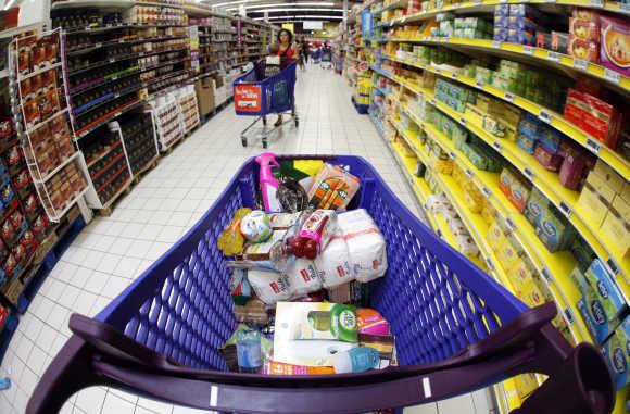 A shopping trolley with food sits parked in an aisle as customers shop at a supermarket in Nice, France.