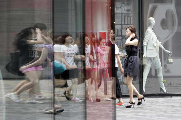 Pedestrians walk past a clothing store in Beijing's Sanlitun Area.