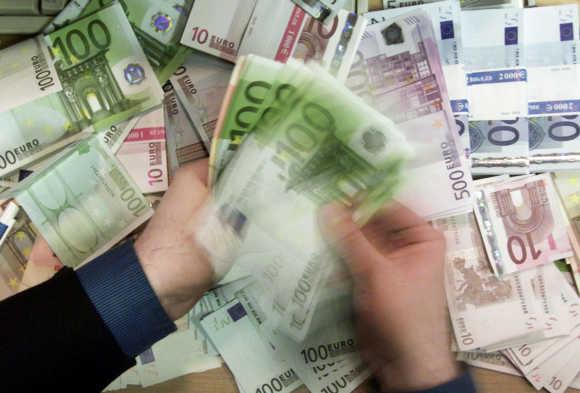 A London bank worker counts out euro bank notes.