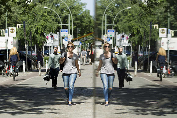 People are reflected in a shop window as they walk in Potsdamer Street in Berlin.