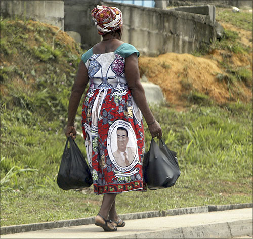 A woman with a picture of Equatorial Guinea's President Teodoro Obiang Nguema Mbasogo on her clothes walks along a street in Bata.