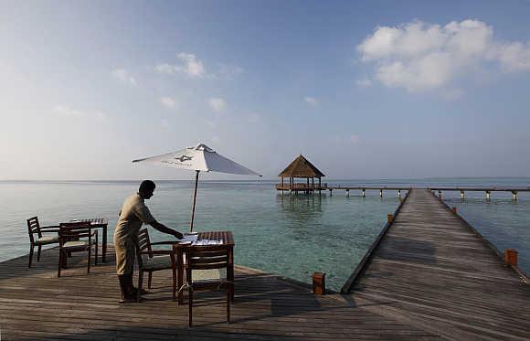 A waiter prepares the table at a restaurant on an island in Maldives.