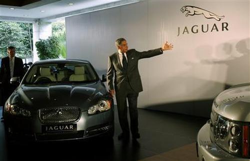 Former Tata Motors chairman Ratan Tata gestures as he stands next to a Jaguar XF during a launch of Jaguar and Land Rover in India.