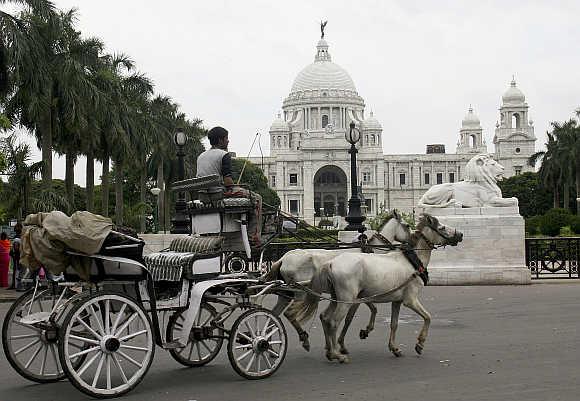 A horse-cart passes in front of the Queen Victoria Memorial in Kolkata.