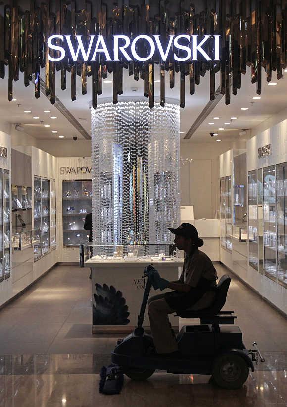 An employee operates a floor cleaning machine in front of a Swarovski showroom inside a mall in Mumbai.