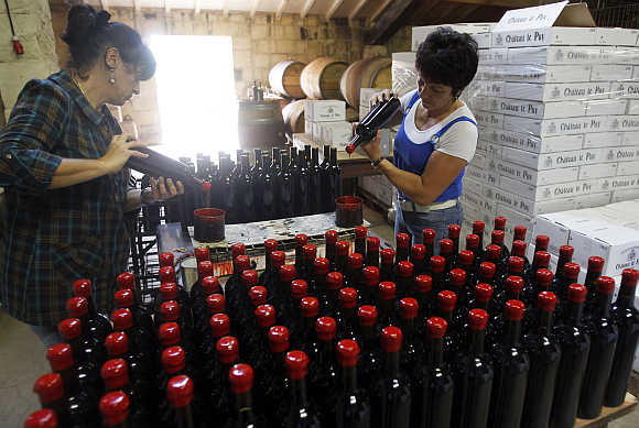 Employees close bottles of wine in the cellar of Chateau Le Puy in Saint Cibard, France.