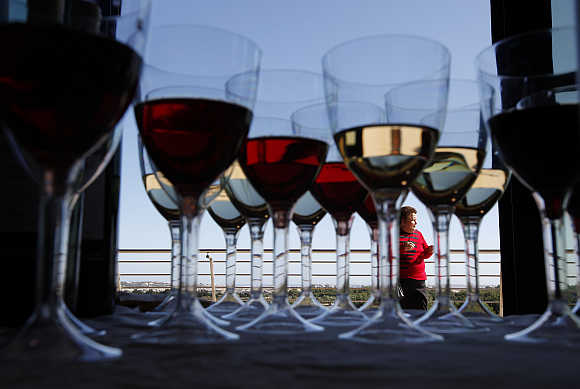 A woman attends the Vivanda Taste the Med food festival as glasses of red and white wine are placed on a display table at Ta' Qali outside Valletta, Malta.