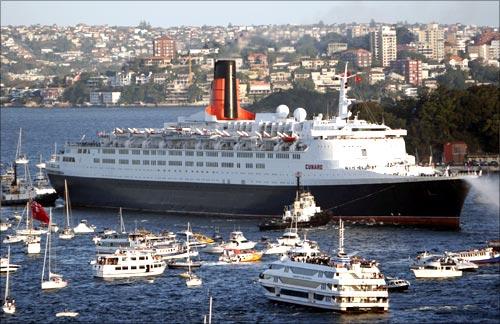 Queen Elizabeth 2 arrives in Sydney harbour, accompanied by a flotilla of small craft.