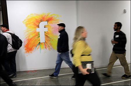 Employees walk past the company logo at the new headquarters of Facebook in Menlo Park.