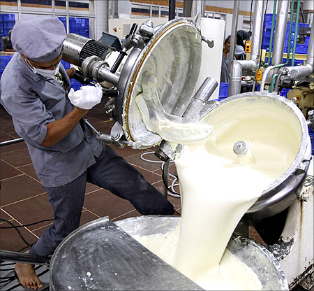 A worker unloads processed cheese from a pressure cooker.