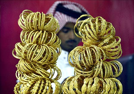 A goldsmith stands behind gold bracelets on display at his shop in Riyadh.