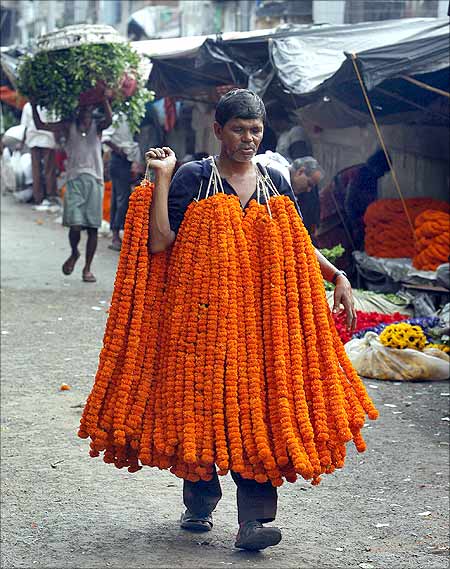 A vendor carries garlands of marigold flowers at a wholesale flower market in Kolkata.