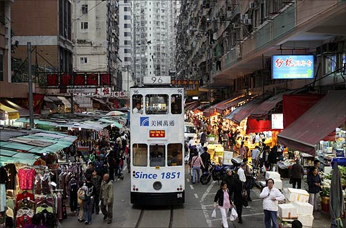 A tram passes by a marketplace in downtown HK.