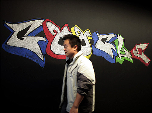 A man walks past a Google logo drawn with chalk.