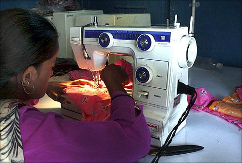 A woman sews clothes on a sewing machine driven by solar energy in Ahmedabad.