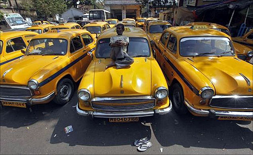 A driver rests on his iconic yellow ambassador taxi in Kolkata.