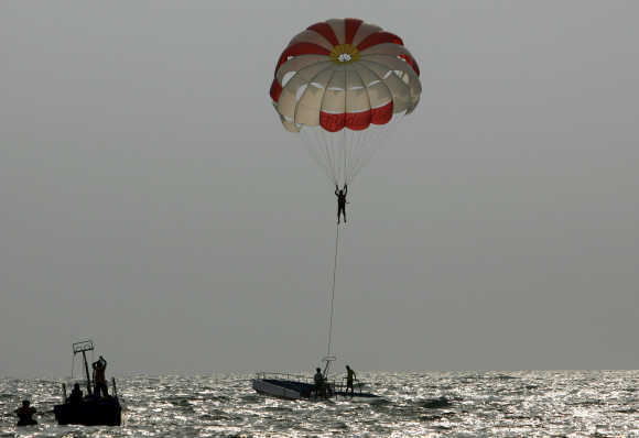 A tourist paraglides on Baga beach in Goa.