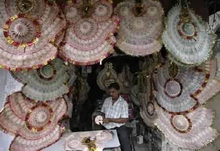 A shopkeeper staples currency notes to make garlands.