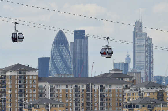 Workers sit in gondolas as they perform tests on the new cable car link across the River Thames in London.