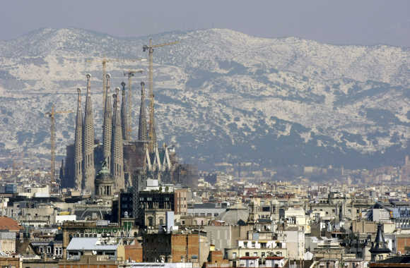 Gaudi's Sagrada Familia and Barcelona's skyline are seen against the backdrop of a snow-covered mount after a snowstorm.